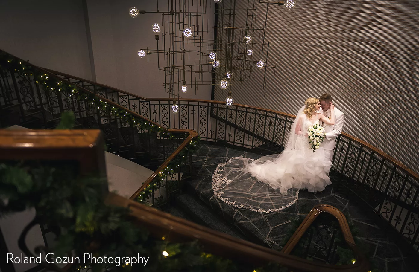Bride and Groom on grand staircase with holiday lights by Roland Gozun Photography